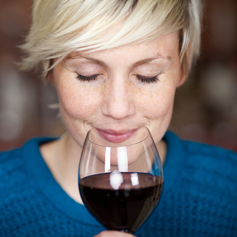 Closeup portrait of a woman sniffing a glass of red wine