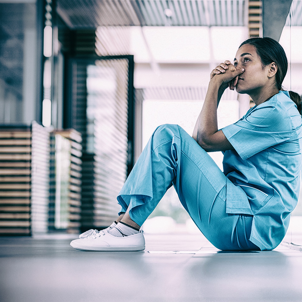 Anxious nurse sitting in hospital corridor