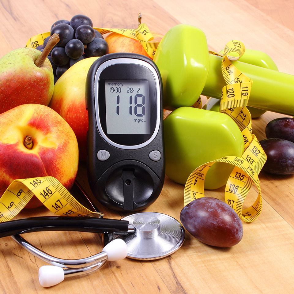 Glucose meter with medical stethoscope, fruits and dumbbells