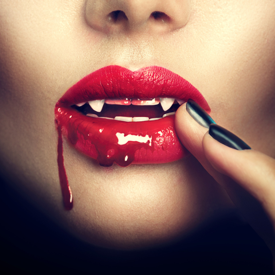 Lips of a female vampire with blood dripping from the corner of her mouth.